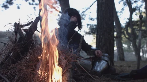Two medieval knights in armor sitting near bonfire and devide production Video stock 124969989