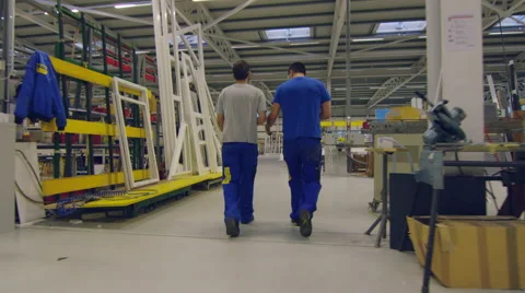 Two members of staff walking and talking while passing through the factory Stock Footage 63023797