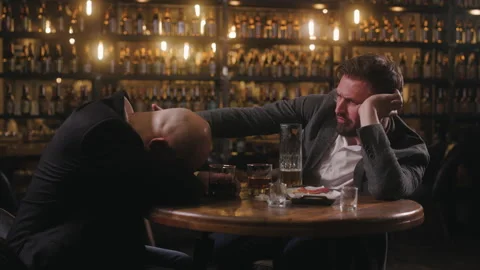 Two men are drinking beer in a bar. The friends got drunk, and one of them fell Stock Footage 278481754