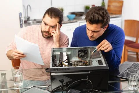 Two men are engaged in assembling a desktop computer Stock-Fotos