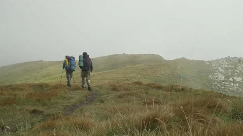 Two men are hiking along a mountain range. Bad weather and cloudy, hiking Stock Footage 238449642
