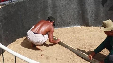 Two men are leveling the sand using a board Stock Footage 323388901