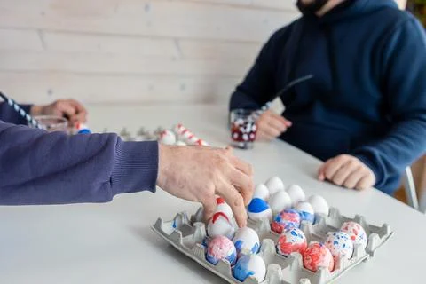 Two men are playing chess with Easter eggs at white table. Creative ideas for Stock Photos