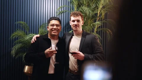 Two men are posing for a picture with wine glasses in their hands Stock Footage 295996930