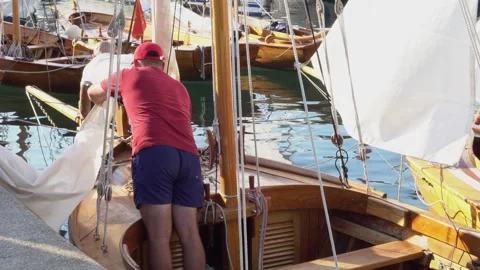Two men are preparing an old sailing yacht to sail from the shore Stock Footage 255438894