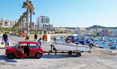 Two men are pulling a boat ashore with the help of a small car Stock Photos