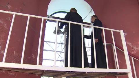 Two men are ringing small bells in the church. Undefined location. Sound. Stock Footage 94921374