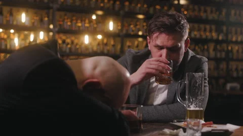 Two men are sitting at a bar, and the scene looks tense. One man has drunkenly Video stock 284087172