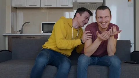 Two men are sitting on the couch and smiling Stock Footage 107646935