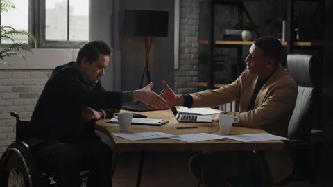 Two men are sitting at a table in an office and shaking hands. Businessmen Stock Footage 241894797