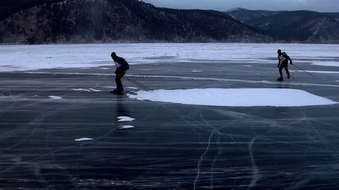 Two men are skating on the ice of frozen Lake Baikal during beautiful sunset. Stock Footage 79548876