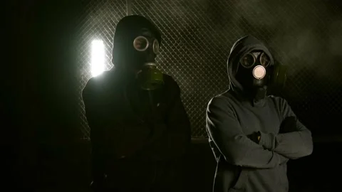 Two men are standing in gas masks with their arms crossed over their chests Stock Footage 169154178