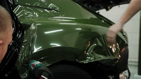 Two men are vinyl wrapping a car in dark green color using heat gun Stock-Footage 171961093