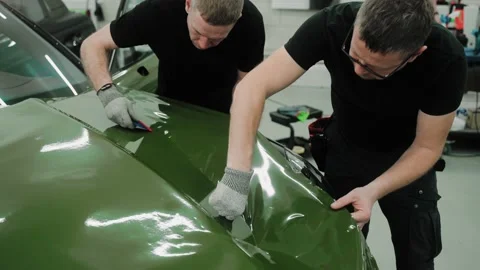 Two men are vinyl wrapping a car in dark green color using plastic cards Vídeo Stock 171962078