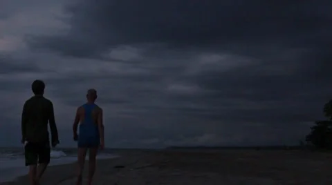 Two men are walking along the beach at night in a storm Stockbeeldmateriaal 33199357