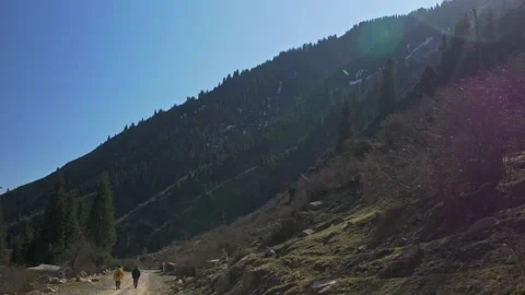Two men are walking along the road, a mountain rises nearby Stock-Footage 241924758