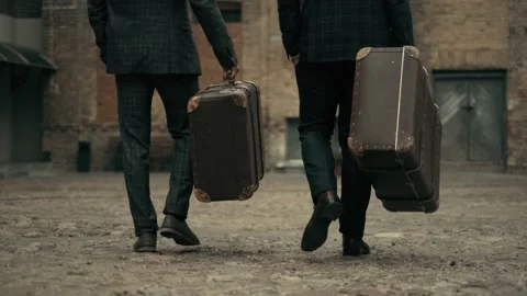 Two men are walking with old vintage suitcase on road. Concept of travel and Vidéo 218718397