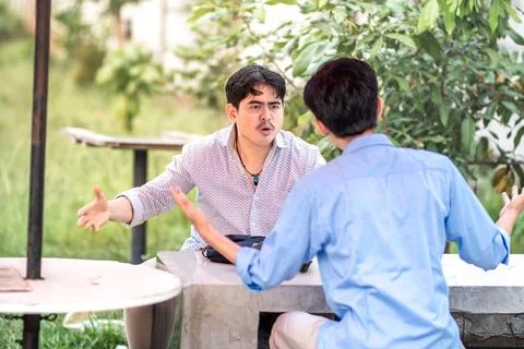 Two men arguing each other in the park. 2 men debate with each other, blame.. Stock Photos