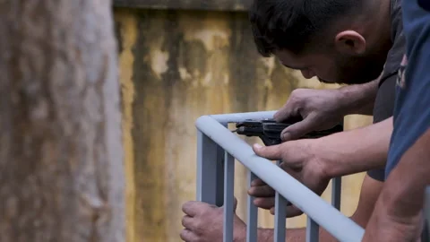 Two men assisting each other in the process of ironing a steel balcony Stock Footage 232382468