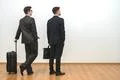 The two men with bags stand on the white wall background Photo