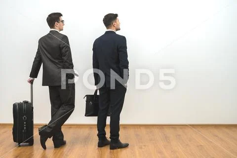 The two men with bags stand on the white wall background Stock Photos