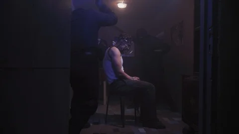 Two men in balaclavas are beating the prisoner with huge black bats, 4k Stock Footage 104037643