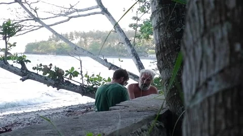 Two men on the beach are eating something. Video stock 137941288