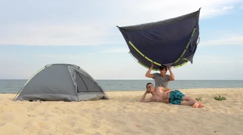 Two men on beach playing with tents. Installing tents in the camping near sea. Stock Footage 66258002