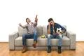The two men with a beer and chips watch a football on the sofa Photo