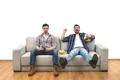 The two men with a beer watch a football on the sofa Photo