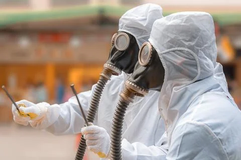 Two men in bio-hazard suits and gas masks. Stock Photos