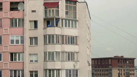 Two men in blue coats remove frames of old windows on balcony of multistoried Stock Footage 132857577