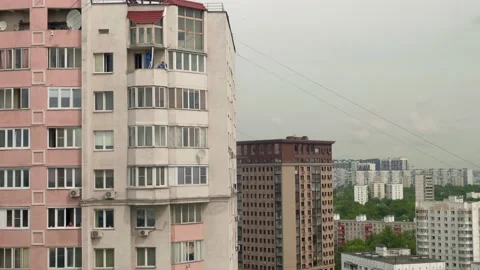 Two men in blue coats remove frames of old windows on balcony of multistoried Stock Footage 132858101