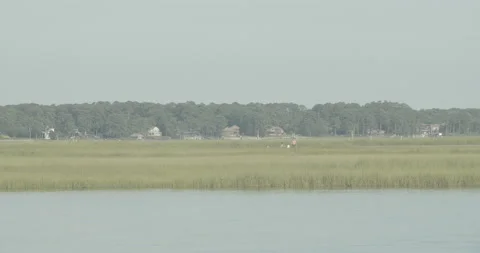 Two Men in Boat on River Beach Houses in Background Video stock 134299702