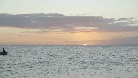 Two men in boat row across sea as sun sets in background Video stock 167561981