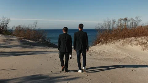 Two men with bottle in classic jackets go to the sea, walking in spring at day. Stock Footage 155489747
