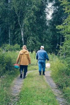 Two men with buckets walk in forest for picking mushrooms Stock Photos