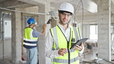 Two men builders smiling confident using touchpad at construction site Stock Footage 245556673