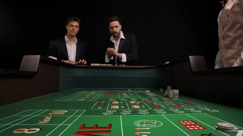 Two men in business suits stand at a green craps table in a casino. The player Stock Footage 155308441