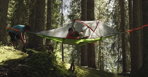 Two men camping with hanging tent in sunny forest. Group of friends summer Stock-Footage 76577945