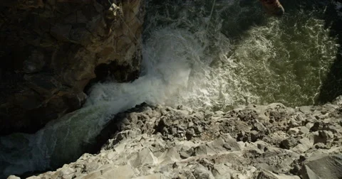 Two men canyoneering down ropes over a huge waterfall in a canyon Stock Footage 64338660