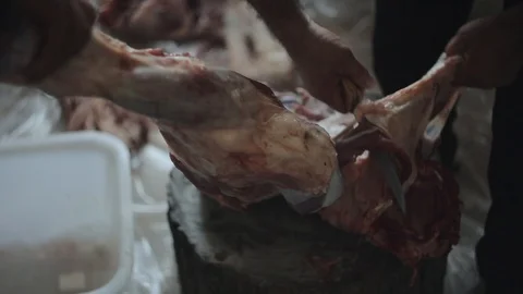 Two men chopping up raw meat. One holds the piece. The other one cuts it with a Видео 96280314