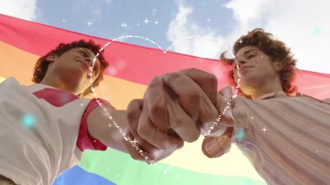 Two men clasping under rainbow flag hands meeting animating heart into sparkle Stock Footage 340750828