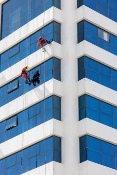 Two men cleaning windows on a skyscraper from outside on harness and ropes .. Foto stock