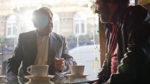 Two men by a coffee shop window in conversation, in slow motion Stock Footage 102305308