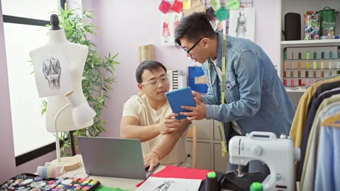 Two men collaborate in a tailor shop with sewing patterns, colorful threads.. Stock Footage 276550328
