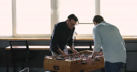 Two men colleagues playing table football in office Stock Footage 221669991