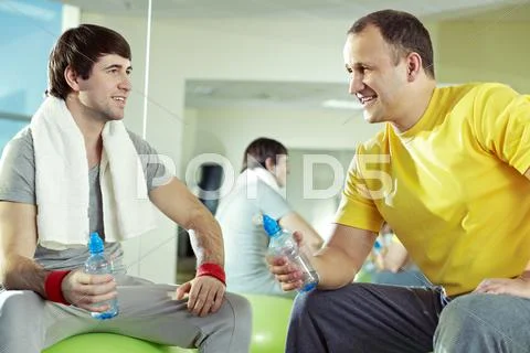 Two men communicating at gym while resting Stock Photos