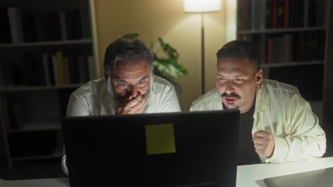Two men at a computer, one covering his face while the other raises both ha.. Stock Footage 339214308