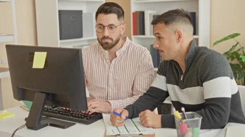 Two men at computer, one typing on a keyboard and the other pointing to a c.. Stock Footage 339218049
